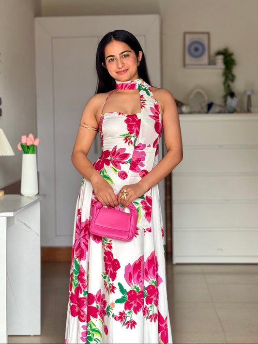 Woman in a floral dress holding a pink handbag indoors.