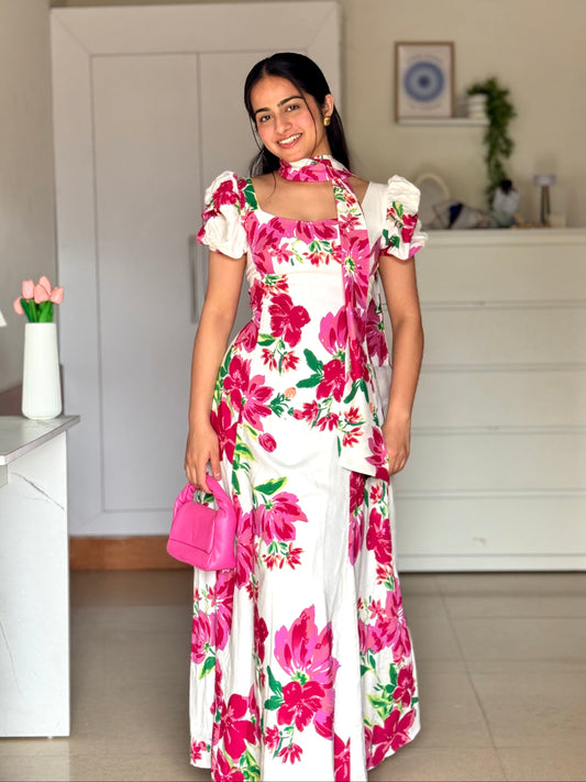 Woman in a floral dress standing in a room with a white cabinet and decor items.